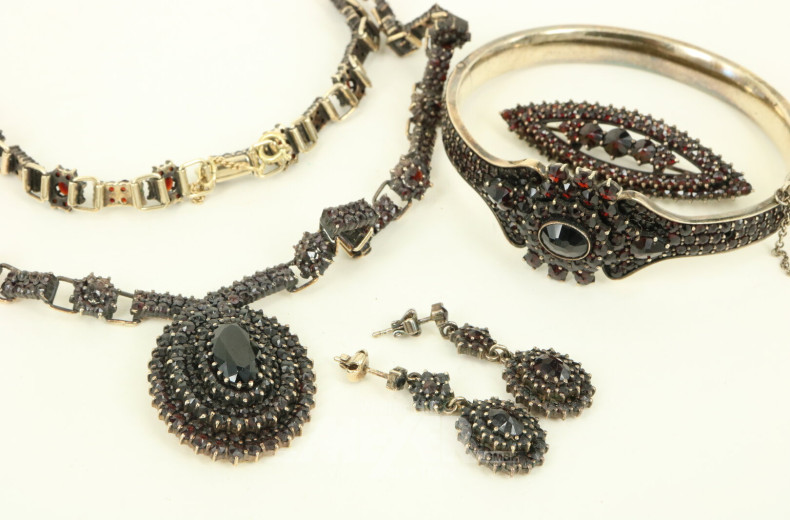 4-tlg. Schmuckset mit Granatbesatz in 900er Silber, best. aus Collier, Brosche, Armreif u. Paar Ohrhänger